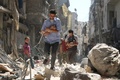 シリア北部アレッポの反体制派支配地域で、空爆の後、赤ちゃんを抱いてがれきの中を逃げる2人の男性（2016年9月11日撮影）。(c)AFP/AMEER ALHALBI