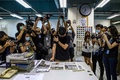 香港の民主派の現地紙「蘋果日報（アップル・デーリー）」編集部で、翌日版の校正をする担当者（中央）を取り囲む報道陣（2021年6月17日撮影）。(c)Anthony WALLACE / AFP