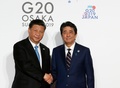 大阪で開催中の20か国・地域（G20）首脳会議の歓迎行事で、中国の習近平国家主席（左）を迎える安倍晋三首相（右、2019年6月28日撮影）。(c)KIM KYUNG-HOON / POOL / AFP