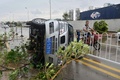 台風14号が上陸した中国・福建省のアモイで、強風のため横転した車のそばを通る男性（2016年9月15日撮影）。(c)AFP