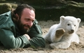 ドイツ・ベルリン（Berlin）の動物園で初めて屋外に出て、飼育係のトーマス・ドーフライン（Thomas Doerflein）さんのかたわらに寝そべって手を振る生後3か月のクヌート（Knut、2007年3月27日撮影）。(c)AFP/JOHN MACDOUGALL