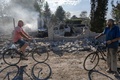 ロシア軍の攻撃で倒壊した建物の横を自転車で行き来する住民。ウクライナ東部ドネツク州クラマトルスクで（2022年7月29日撮影）。(c)Bulent KILIC / AFP