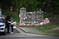米テネシー州ナッシュビルの小学校コブナント・スクール前で、銃乱射事件の犠牲者のために手向けられた花束などのそばで、警察官と抱擁を交わす女性（2023年3月28日撮影）。(c)Brendan SMIALOWSKI / AFP
