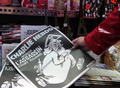 仏パリの売店で、風刺週刊紙シャルリー・エブドの本社襲撃事件1年特別号を手にとる女性（2016年1月6日撮影、資料写真）。(c)AFP/JACQUES DEMARTHON