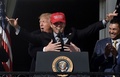 「アメリカを再び偉大に」と書かれた赤い帽子をかぶったワシントン・ナショナルズのカート・スズキ（中央）をハグするドナルド・トランプ大統領（後方、2019年11月4日撮影）。(c)Olivier Douliery / AFP