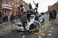 暴動が起きた米メリーランド州ボルティモアで、破壊された警察車両の上に立つ人々（2015年4月27日撮影）。(c)AFP/Getty Images/Chip Somodevilla