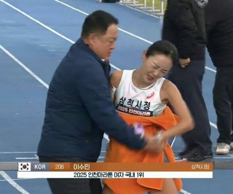 2025年仁川国際マラソンで、女子国内1位の選手がゴールした直後、キム監督がタオルで上半身を覆う様子＝KBS中継画面(c)news1