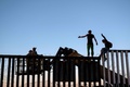 メキシコ・プラヤスデティフアナで、移民キャラバンの一員ではないと主張しつつ、米国との国境フェンス上の有刺鉄線を外して国防総省の職員と口論する移民ら（2018年11月14日撮影）(c)Guillermo Arias / AFP