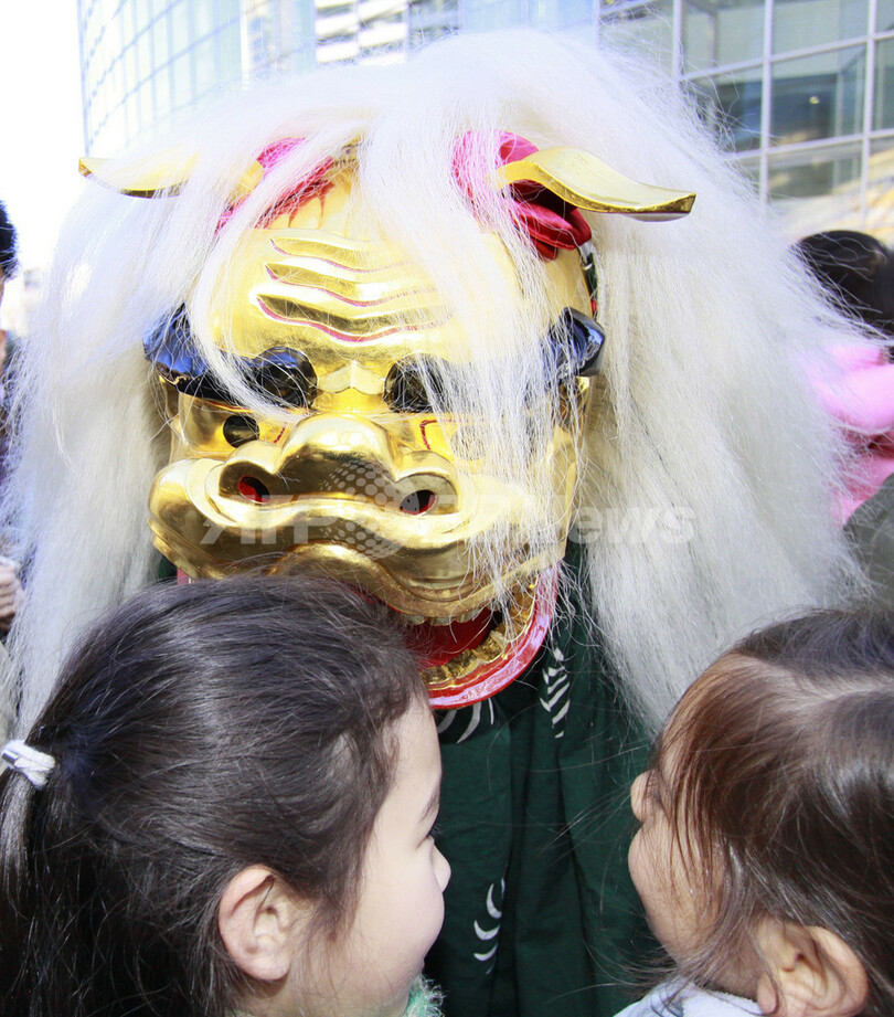 新年の幸運を願って獅子舞がガブリ、東京