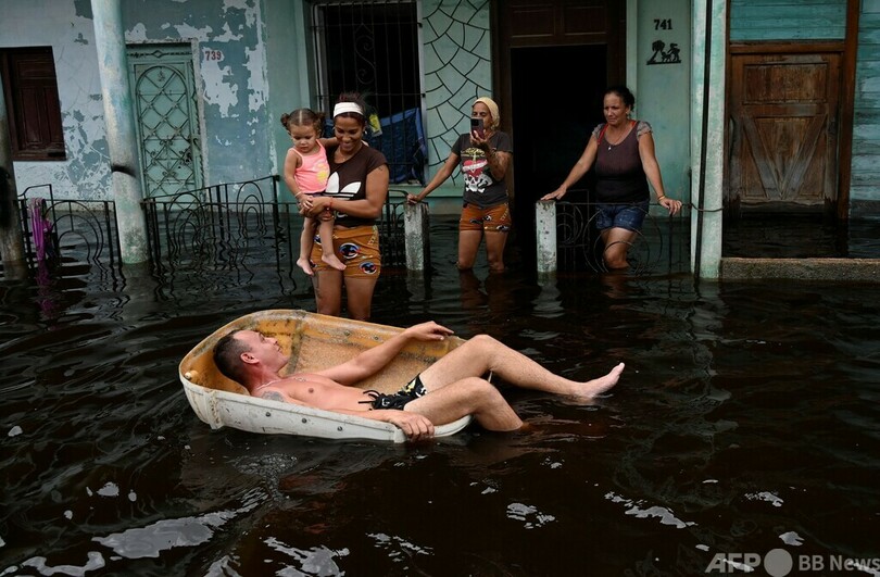【今日の1枚】ハリケーン一過、冠水した通りを浮き具で移動する男性 キューバ