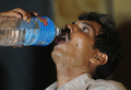 インド・マンガロール（Mangalore）の病院で、政府の保健当局者に水を飲ませてもらっている男性(2010年5月22日撮影)。(c)AFP/Dibyangshu SARKAR