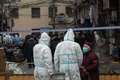 中国・上海の黄浦区で、隔離対象となった住宅街周辺を封鎖する防護服姿の警察官ら（2021年1月21日撮影）。(c)STF / AFP