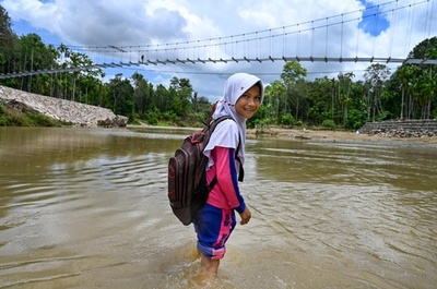 つり橋は建設途上、歩いて川を渡る人たち インドネシア