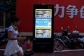 中国の上海市街で、交差点で信号無視をした人たちを顔認証技術システムで撮影した画像を映し出すスクリーン（2017年8月9日撮影）。(c)AFP/CHANDAN KHANNA 