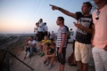 イスラエル南部スデロット（Sderot）で、パレスチナ自治区ガザ地区（Gaza Strip）を見下ろす丘の上に集まり、空爆やロケット弾による双方の攻撃の様子を見るイスラエル人たち（2014年7月9日撮影）。(c)AFP/MENAHEM KAHANA