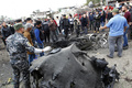 イラクの首都バグダッドのサドルシティーで、爆発現場にある焼け焦げた自動車を調べる治安部隊員（2017年1月2日撮影）。(c)AFP/SABAH ARAR