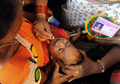 インド・ハイデラバード（Hyderabad）で8日、Bathini Goudさんによる「魚療法（Fish Medicine）」が行われ、投薬を受けるために全国から数千人が集まった。「魚療法」はぜんそくなどの気管支系疾患に効くとして、同国南部に暮らすこの一家が158年前から代々行っている療法で、薬草から作られた秘伝の薬を生きた魚にくわえさせ、順番に患者の口の中に落としていくというもの。投薬は6月のモンスーン到来とともに訪れる縁起の良い日「Mrigasira Karti」に行われる。写真は、患者に投薬するBathini Goudさんの家族（右、2009年6月8日撮影）。(c)AFP/Noah SEELAM
