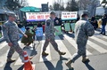 韓国ソウルの外務省前で、米軍の最新鋭迎撃システム「高高度防衛ミサイル（THAAD、サード）」配備に反対する人々の前を横切る米兵ら（2016年2月23日撮影、資料写真）。(c)AFP/JUNG YEON-JE
