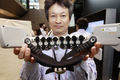 都内で開催中の日立（Hitachi）のコンベンションで、｢光トポグラフィ技術｣を使って人の大脳皮質内の変化を読み取り、データを無線送信、このデーター分析基づいて機器を操作する｢ブレイン・マシン・インターフェース（BMI）｣研究の開発器具を披露するエンジニア（2010年7月22日撮影）。(c)AFP/Yoshikazu TSUNO