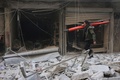 シリア北部アレッポの反体制派支配地区で、空爆により破壊されたとされる建物のがれきの中を歩く男性（2016年2月4日撮影）。(c)AFP/THAER MOHAMMED