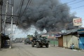 イスラム武装勢力の襲撃を受けたフィリピン南部ミンダナオ（Mindanao）島の商業都市サンボアンガ（Zamboanga）では、12日も治安当局と和平協議に応じないイスラム反政府勢力との戦いが2か所の戦線で続いている。同国政府は、炎に包まれた複数の地区を奪還した。

サンボアンガでは、4日間にわたる戦闘で数千人が避難を強いられている。フィリピン軍報道官によると、同市のサンタカタリナ（Santa Catalina）地区では、治安部隊が進軍する中、家々が炎に包まれた。

警察の支援を受けた少なくとも1500人の兵士が、サンボアンガ郊外のイスラム教徒が多く住む6地区を包囲。これらの地域では、反政府勢力「モロ民族解放戦線（MNLF）」のメンバー約180人が、9日に攻撃を開始して以降潜伏を続けている。反政府勢力は数十人の人々を「人間の盾」にしているため、市民が負傷することを避けたい治安部隊との間でこう着状態が続いている。

写真はサンボアンガで、煙を上げる家々の近くで反政府勢力への攻撃に備える兵士ら（2013年9月12日撮影）。(c)AFP/TED ALJIBE