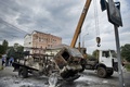 ウクライナの港湾都市マリウポリ（Mariupol）で、一方的に樹立を宣言した「ドネツク人民共和国」の焼けた軍用車両を撤去する作業員ら（2014年6月13日撮影）。(c)AFP/DANIEL MIHAILESCU