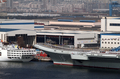 中国初めての空母「遼寧（Liaoning）」が25日、正式に就役した。中国国防省が発表した。

中国初の空母は、ウクライナから購入した旧ソ連の空母「ワリャーグ（Varyag）」を遼寧（Liaoning）省大連（Dalian）で改修したもので、その省名から名称がつけられた。

写真は大連の海軍基地に係留された「遼寧（Liaoning）」（右、2012年9月25日撮影）。(c)AFP