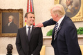 米首都ホワイトハウスの大統領執務室で、エマニュエル・マクロン仏大統領（左）の「ふけ」を払うドナルド・トランプ米大統領（2018年4月24日撮影）。(c)AFP PHOTO / ludovic MARIN