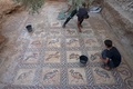 パレスチナ自治区ガザ地区で、ビザンツ帝国時代のモザイク画を清掃する発見者の男性と息子（2022年9月18日撮影）。(c)MOHAMMED ABED / AFP