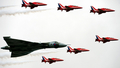 英南部のハンプシャー（Hampshire）で9日、ファンボロー国際航空ショー（Farnborough International Airshow）が開幕した。債務に苦しむ各国政府が軍事費を削減している中、今回のショーで発表される軍用機の大型契約は少ないとみられる。

写真は、デモ飛行する英空軍のアクロバットチーム、レッドアローズ（Red Arrows）とバルカン（Vulcan）爆撃機（2012年7月9日撮影）。(c)AFP/ADRIAN DENNIS