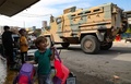 シリア北部の対トルコ国境沿いにあるクルド人の町タルアブヤドで、トルコ側につく戦闘員が乗る軍用車両を見る子どもたち（2019年10月23日撮影）。(c)Zein Al RIFAI / AFP