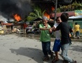 イスラム武装勢力の襲撃を受けたフィリピン南部ミンダナオ（Mindanao）島の商業都市サンボアンガ（Zamboanga）では、12日も治安当局と和平協議に応じないイスラム反政府勢力との戦いが2か所の戦線で続いている。同国政府は、炎に包まれた複数の地区を奪還した。

サンボアンガでは、4日間にわたる戦闘で数千人が避難を強いられている。フィリピン軍報道官によると、同市のサンタカタリナ（Santa Catalina）地区では、治安部隊が進軍する中、家々が炎に包まれた。

警察の支援を受けた少なくとも1500人の兵士が、サンボアンガ郊外のイスラム教徒が多く住む6地区を包囲。これらの地域では、反政府勢力「モロ民族解放戦線（MNLF）」のメンバー約180人が、9日に攻撃を開始して以降潜伏を続けている。反政府勢力は数十人の人々を「人間の盾」にしているため、市民が負傷することを避けたい治安部隊との間でこう着状態が続いている。

写真はサンボアンガで火に包まれる家々から病人を避難させる人々（2013年9月12日撮影）。(c)AFP/TED ALJIBE