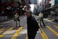 香港の旺角地区で、違法屋台の取り締まりに抗議する人と警官隊の衝突を受けて封鎖された道路を通り過ぎる男性（2016年2月9日撮影）。(c)AFP/DALE DE LA REY