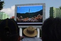 北朝鮮・平壌市内で、大陸間弾道ミサイル（ICBM）発射実験の様子を伝える放送を見る人々（2017年7月4日撮影）。(c)AFP/Kim Won-Jin