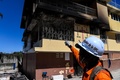 火災のあったハイチの首都ポルトープランス南郊ケンスコフにある無認可孤児院「聖書理解教会の孤児院」の建物を指さす消防隊員（2020年2月14日撮影）。(c)CHANDAN KHANNA / AFP