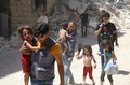シリア北部アレッポで反体制勢力が制圧するマシャド地区に対する空爆現場から、子供を連れて避難する人々（2016年7月25日撮影）。(c)AFP/Baraa Al-Halabi