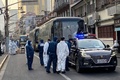 中国・上海の黄浦区の隔離対象となった住宅街で、バスのそばに立つ防護服姿の警察官ら（2021年1月21日撮影）。(c)STF / AFP