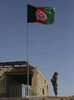 アフガニスタン南部ヘルマンド（Helmand）州マルジャ（Marjah）の市場の建物に掲揚されたアフガニスタン国旗に敬礼するアフガニスタン国軍の兵士（2010年2月17日撮影）。(c)AFP/Altaf Qadri