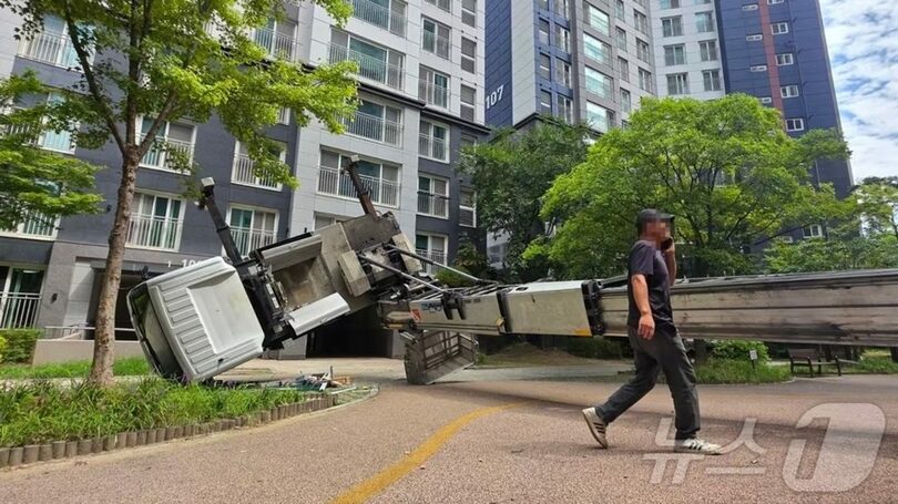 26日、韓国・天安市東南区新富洞のマンションで引っ越し用のはしご車が倒れ、業者関係者が撤去方法を協議している。この事故で登校中の小学生1人が負傷した。2026年8月26日(c)news1