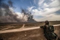 シリア東部デリゾール県バグズ村で、立ち上る煙を見つめるクルド人主体の民兵組織「シリア民主軍（SDF）」の兵士（2019年3月13日撮影）。(c)Delil souleiman / AFP