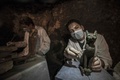 エジプトの古代都市サッカラの発掘現場で新たに発見された猫の銅像をクリーニングする考古学者（2018年11月10日撮影）。(c)KHALED DESOUKI / AFP