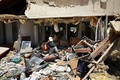 イスラエル南部ベエルシェバ（Beersheva）で、夜間にパレスチナ自治区ガザ地区（Gaza Strip）の武装勢力からロケット弾攻撃を受けた家屋の被害状況を調べる住民（2014年7月12日撮影）。(c)AFP/MENAHEM KAHANA