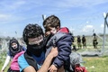 ギリシャ・イドメニの対マケドニア国境で、マケドニア警察と移民や難民が衝突する中、催涙ガス対策として顔面に練り歯磨きを塗り、安全な場所へ逃げる家族（2016年4月10日撮影）。(c)AFP/BULENT KILIC