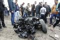イラクの首都バグダッドのサドルシティーで、爆発現場にある焼け焦げた自動車の周囲に集まった人々（2017年1月2日撮影）。(c)AFP/SABAH ARAR