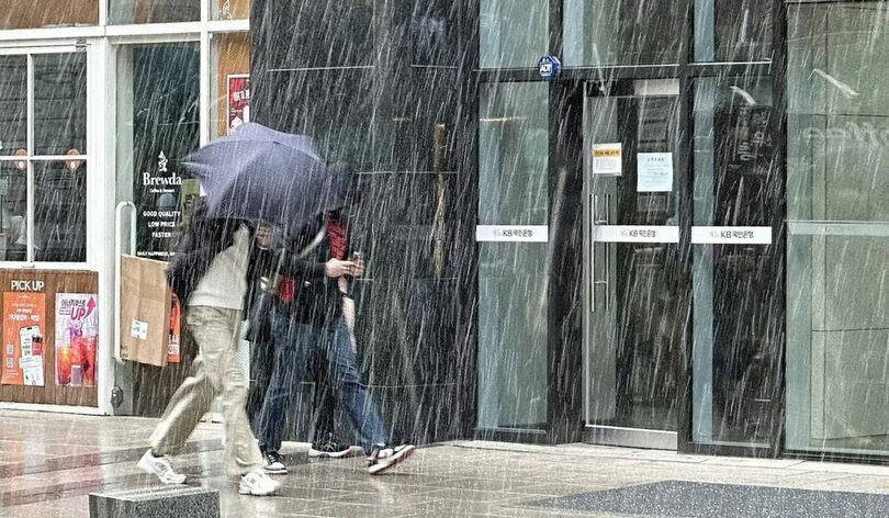 2025年4月13日、ソウル市鍾路区で、4月中旬としては118年ぶりとなる降雪に見舞われ足早に歩く市民(c)news1