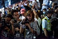 民主派による抗議行動が続く香港（Hong Kong）・旺角（Mongkok）地区で、警官隊に押された自分を助けようとして催涙スプレーを浴び、倒れ込んだ同僚のカメラマンを涙ながらに撮影する女性ジャーナリスト（中央、2014年10月17日撮影）。(c)AFP/ALEX OGLE