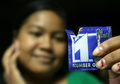 カンボジアの首都プノンペン（Phnom Penh）で、コンドーム用潤滑剤「ナンバー・ワン・プラス（Number One Plus）」を顔に塗った後、パッケージを見せる女性（2008年8月28日撮影）。(c)AFP/TANG CHHIN SOTHY
