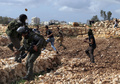 パレスチナ自治区ヨルダン川西岸（West Bank）で、イスラエルの境界を警備するイスラエル軍兵士に投石するパレスチナ人の少年たちと、拘束しようとするイスラエル軍兵士（2013年3月1日撮影）。(c)AFP/ABBAS MOMANI