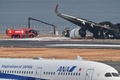 海上保安庁の航空機と衝突した日本航空（JAL）の旅客機（右奥）。東京国際（羽田）空港で（2024年1月3日撮影）。(c)Richard A. Brooks / AFP