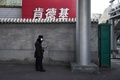 中国・北京で、商店街そばの路地でマスクをして立つ警備員（2020年2月17日撮影）。(c)GREG BAKER / AFP